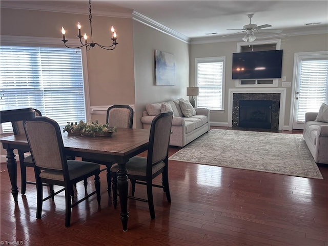 dining room featuring dark wood finished floors, a fireplace with flush hearth, ceiling fan with notable chandelier, and ornamental molding