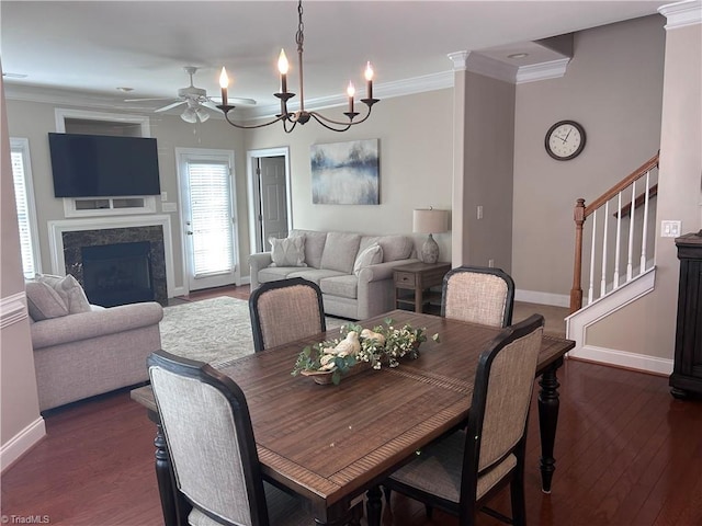 dining room featuring stairway, ornamental molding, dark wood-style flooring, and ceiling fan with notable chandelier