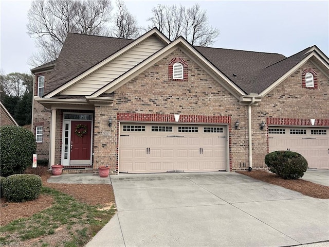 view of front facade with brick siding, an attached garage, a shingled roof, and driveway