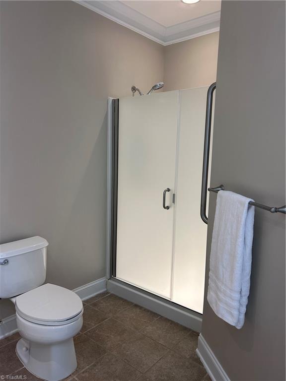 bathroom with crown molding, toilet, and baseboards