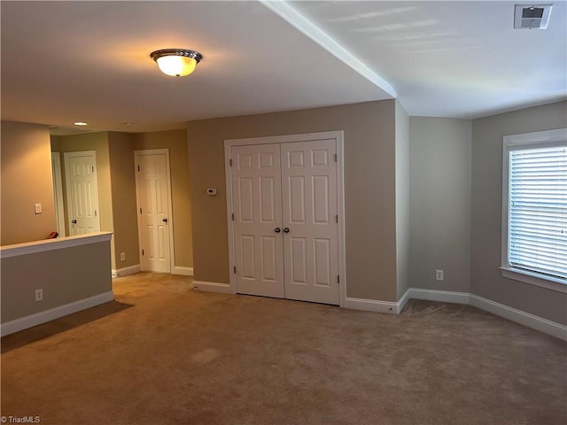 unfurnished bedroom with visible vents, baseboards, light colored carpet, and a closet