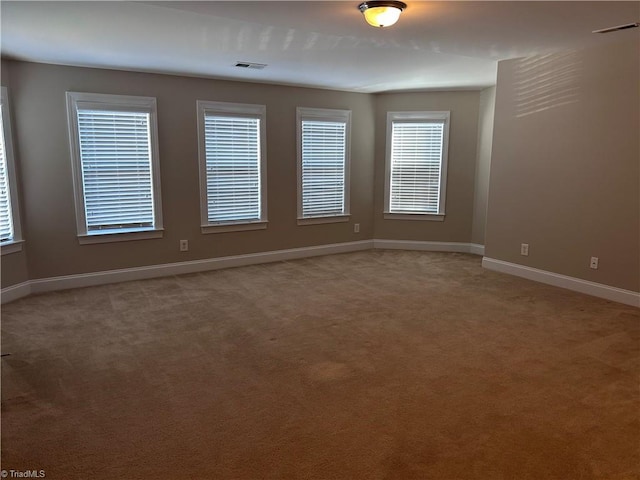 spare room with light colored carpet, visible vents, and baseboards