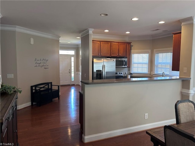 kitchen featuring brown cabinets, dark wood-type flooring, ornamental molding, dark countertops, and appliances with stainless steel finishes