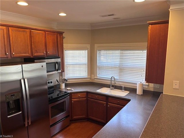 kitchen with visible vents, a sink, crown molding, appliances with stainless steel finishes, and dark countertops