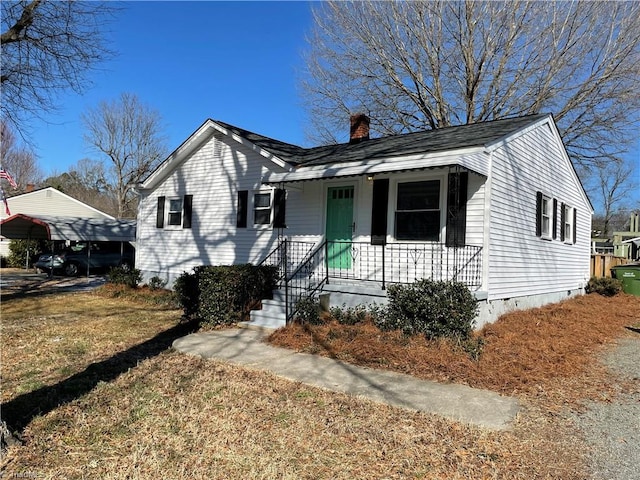 view of front of home with covered porch, a front yard, and a carport