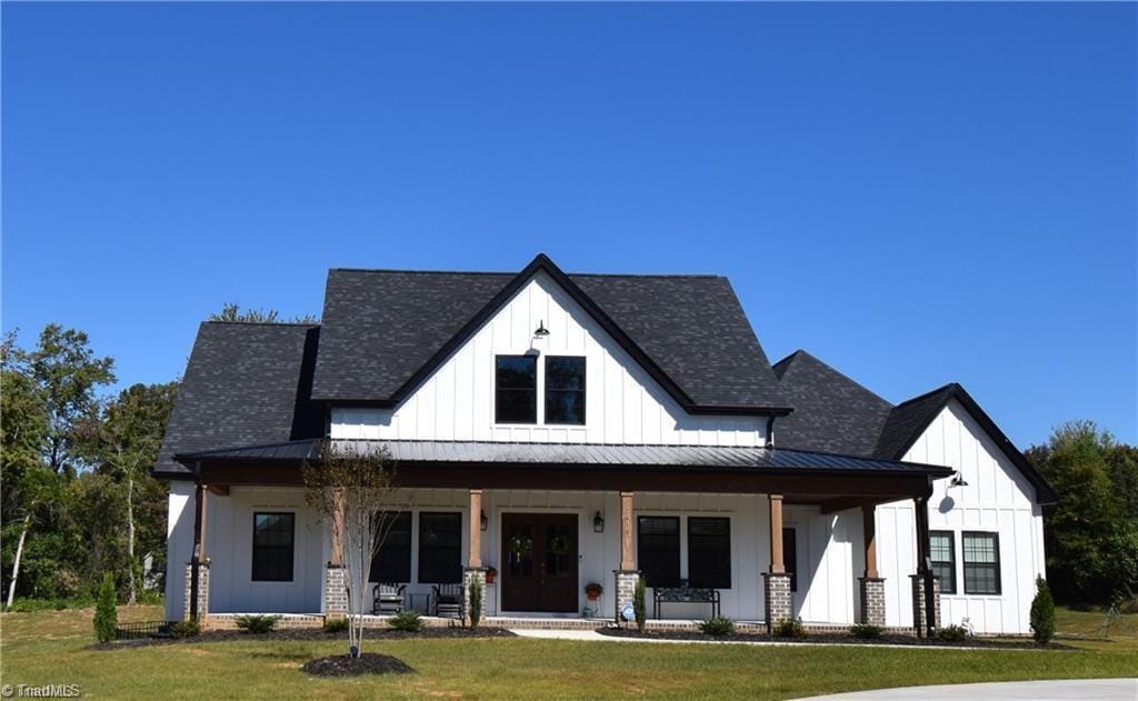 modern inspired farmhouse with a front yard and covered porch