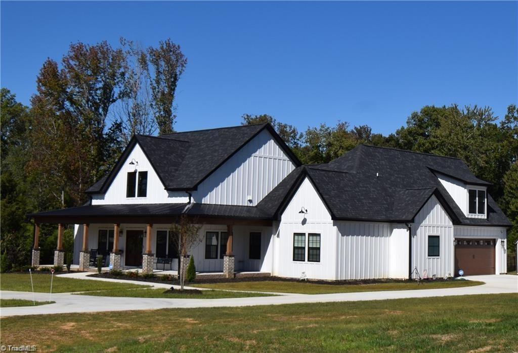 modern inspired farmhouse featuring a garage, covered porch, and a front lawn