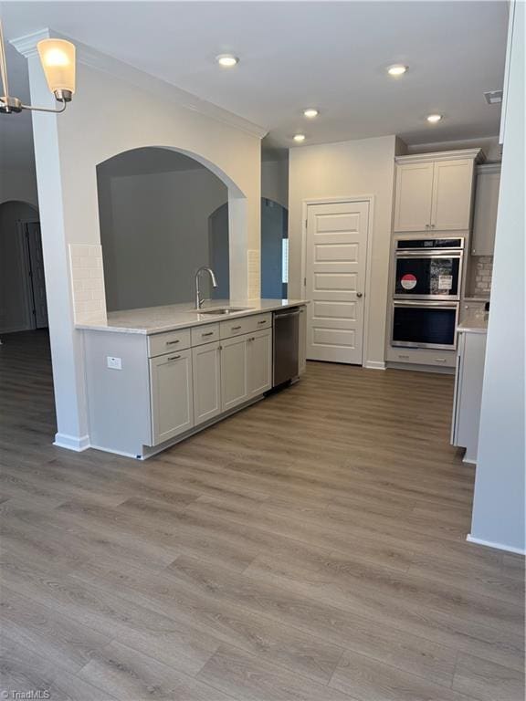 kitchen with light wood-type flooring, sink, appliances with stainless steel finishes, and tasteful backsplash