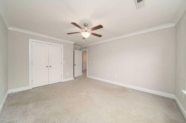 unfurnished bedroom featuring crown molding, light colored carpet, a closet, and ceiling fan