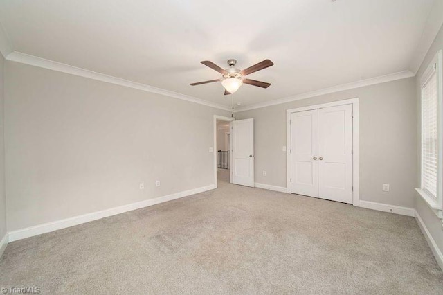 unfurnished bedroom featuring crown molding, light colored carpet, ceiling fan, and a closet