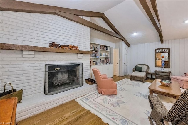 living room featuring light wood-style floors, vaulted ceiling with beams, and a brick fireplace
