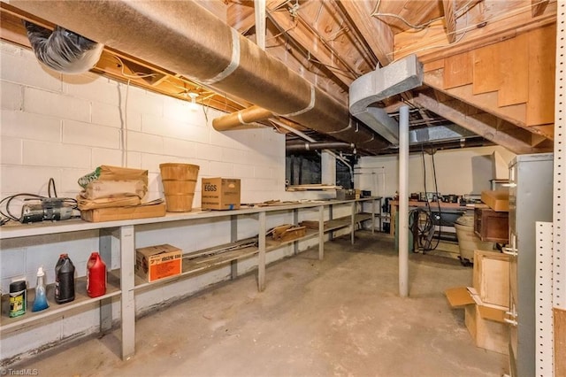 unfinished basement featuring concrete block wall and a workshop area