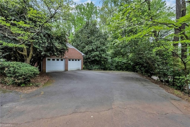 view of home's exterior featuring brick siding, driveway, and a garage