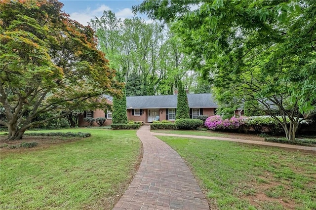 single story home with brick siding, a chimney, and a front lawn