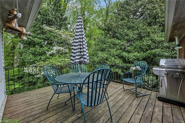 wooden terrace with outdoor dining area and a grill