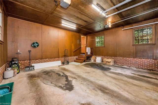 misc room featuring wood ceiling, wooden walls, brick wall, and unfinished concrete floors