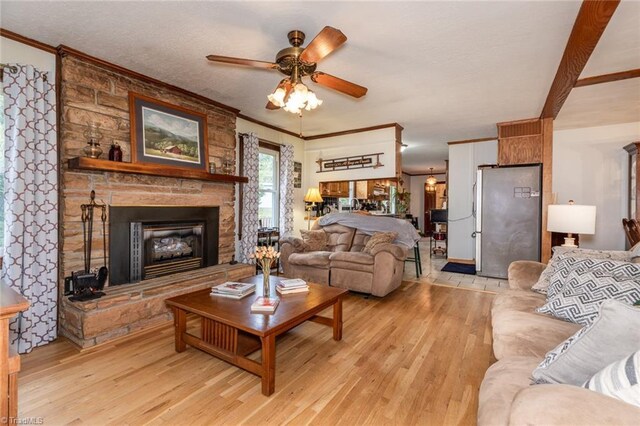 living room featuring a fireplace, crown molding, light hardwood / wood-style flooring, and ceiling fan