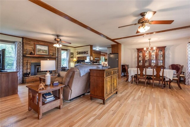 living room with a stone fireplace, light hardwood / wood-style flooring, and ceiling fan with notable chandelier