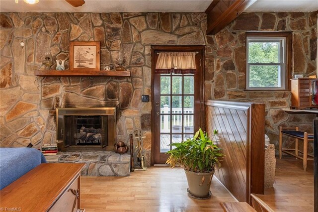 living room featuring ceiling fan, a wealth of natural light, light hardwood / wood-style floors, and a stone fireplace