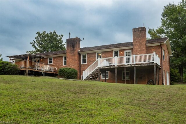 rear view of house featuring a wooden deck and a lawn