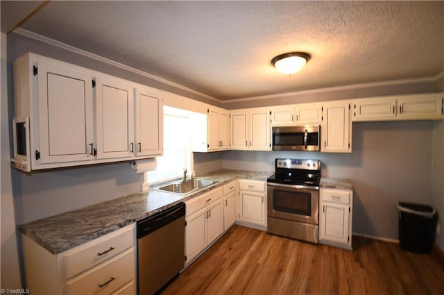 kitchen with stainless steel appliances, hardwood / wood-style flooring, sink, and white cabinets