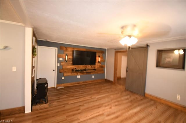 unfurnished living room with crown molding, wood-type flooring, and a barn door