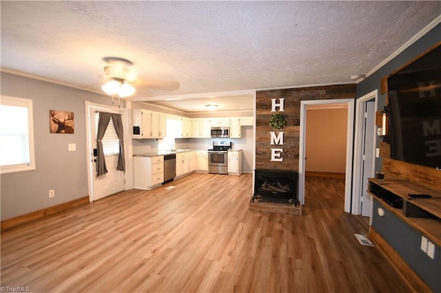 kitchen with stainless steel appliances, light wood-type flooring, a textured ceiling, and white cabinets