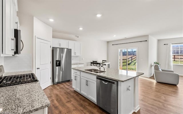 kitchen with sink, white cabinetry, light stone countertops, a center island with sink, and appliances with stainless steel finishes