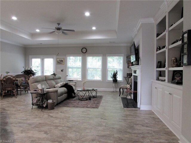 living area with a tray ceiling, ceiling fan, recessed lighting, crown molding, and a fireplace