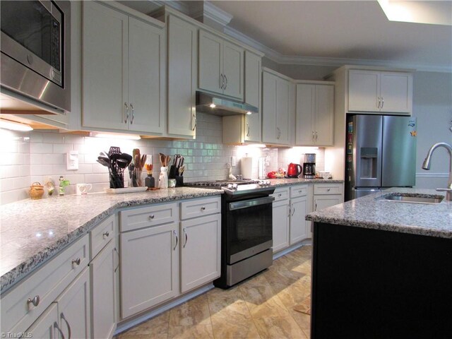 kitchen with appliances with stainless steel finishes, a sink, under cabinet range hood, and tasteful backsplash