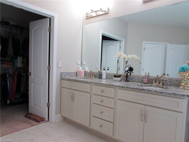 full bath featuring marble look tile flooring, double vanity, and a spacious closet