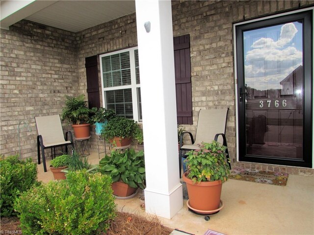 entrance to property with covered porch and brick siding
