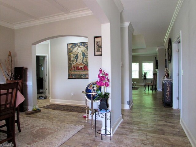 hallway featuring crown molding, arched walkways, and baseboards