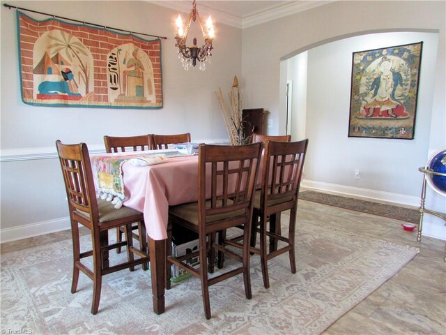 dining room featuring arched walkways, ornamental molding, a chandelier, and baseboards