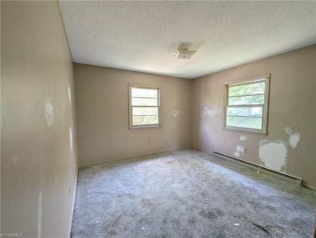 empty room featuring a healthy amount of sunlight, a baseboard radiator, and a textured ceiling