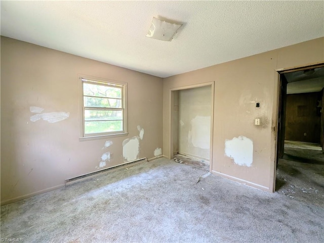 unfurnished bedroom featuring carpet floors, a textured ceiling, baseboard heating, and a closet