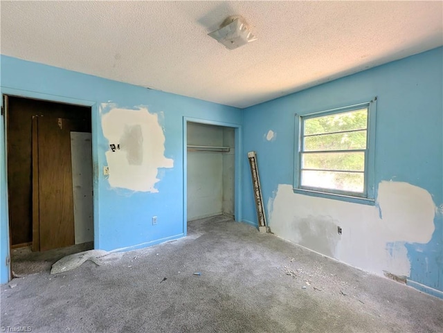 unfurnished bedroom with a closet, carpet, a textured ceiling, and baseboards