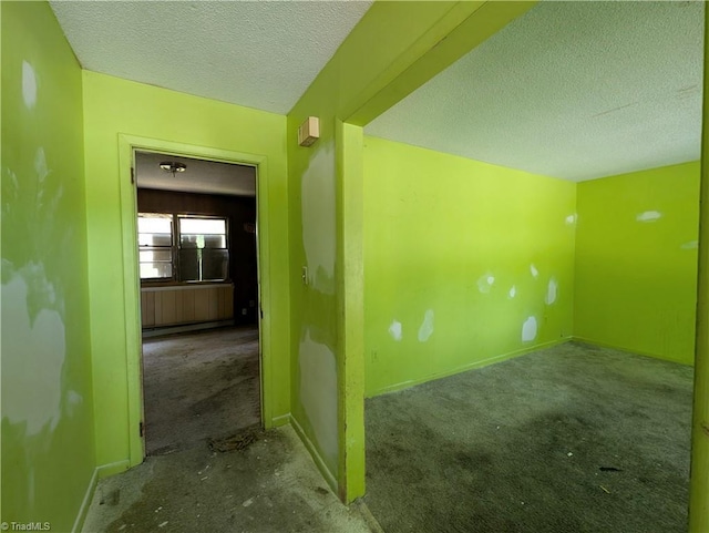 carpeted empty room with baseboards and a textured ceiling
