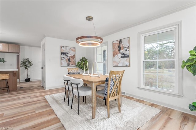 dining area featuring ornamental molding and light wood-type flooring