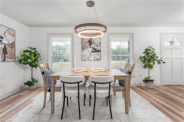 dining space featuring crown molding, a healthy amount of sunlight, and light hardwood / wood-style flooring