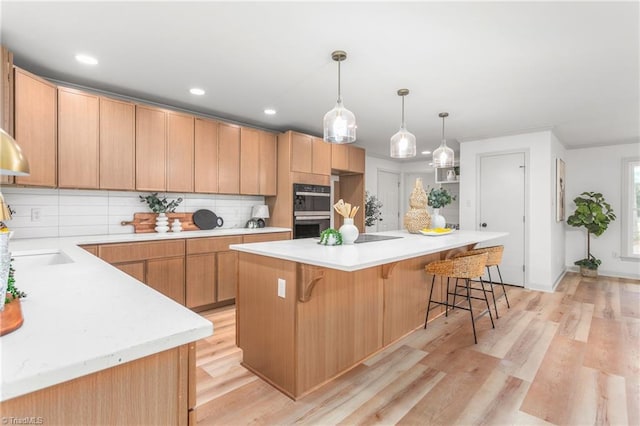 kitchen with black double oven, a center island, light hardwood / wood-style floors, and backsplash