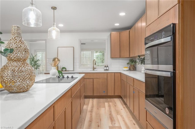 kitchen with double oven, decorative light fixtures, sink, decorative backsplash, and black electric stovetop