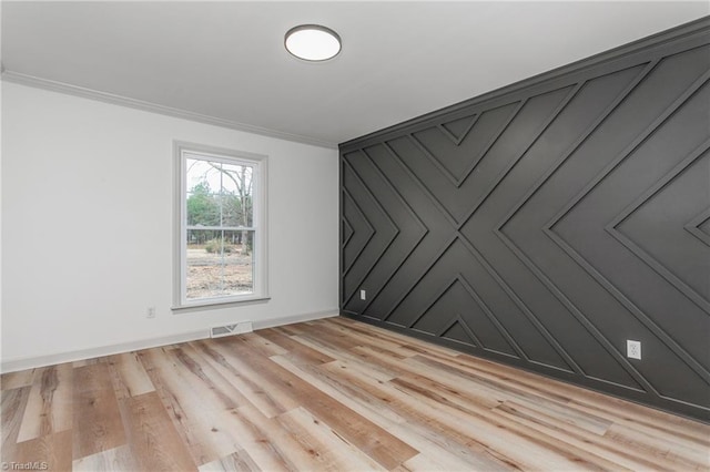 spare room featuring crown molding and light hardwood / wood-style floors