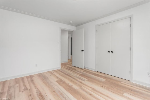 unfurnished bedroom with crown molding, light hardwood / wood-style flooring, and a closet