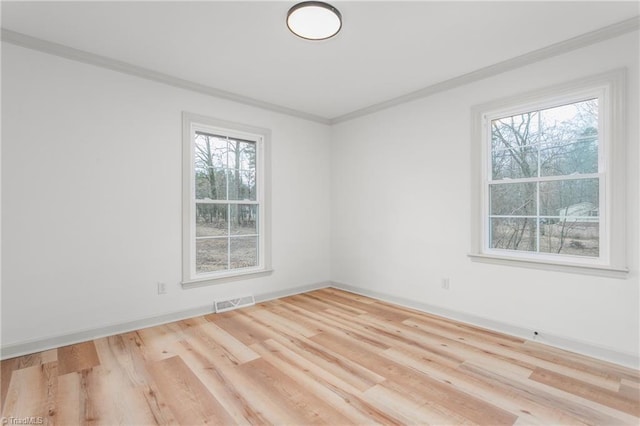 empty room with crown molding and light hardwood / wood-style floors
