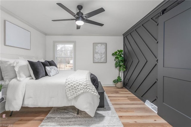 bedroom featuring crown molding, wood-type flooring, and ceiling fan