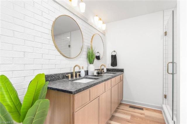 bathroom featuring wood-type flooring, walk in shower, vanity, and decorative backsplash