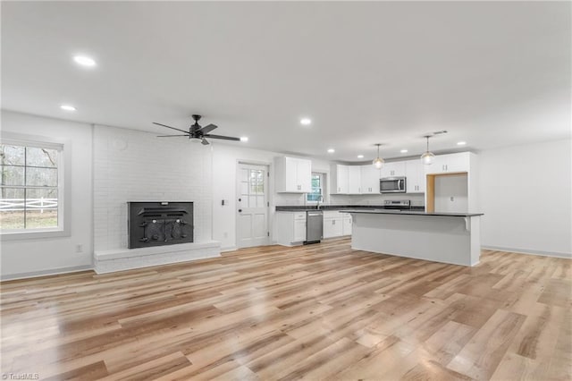 kitchen with appliances with stainless steel finishes, light wood-type flooring, hanging light fixtures, and white cabinets