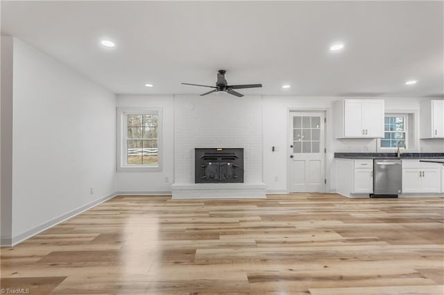 unfurnished living room featuring ceiling fan, a fireplace, and light hardwood / wood-style floors