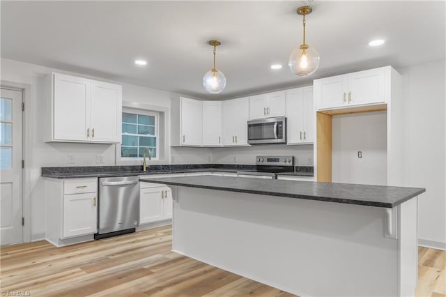 kitchen with white cabinetry, hanging light fixtures, stainless steel appliances, a center island, and light hardwood / wood-style floors